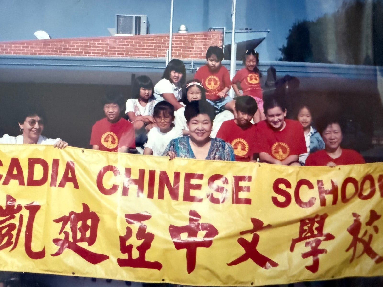 With a larger group of students at the school banner